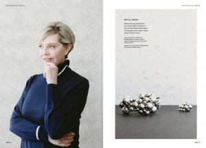 A blonde model wearing a blue turtleneck knit jumper and silver accessories.