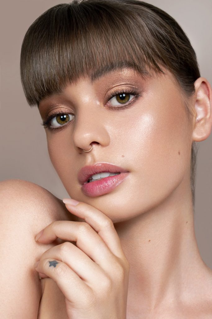 Model Jordan De Alvia wearing bronze eyeshadow with her finger on her chin.