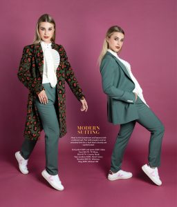 A blonde model wearing an olive green suit with a green and orange leopard jacket over the top.